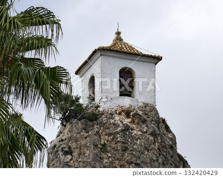 intimate view of traditional bell chamber nestled among rocky surroundings and lush palm leaves intimate view of traditional bell chamber nestled among rocky surroundings and lush palm leaves 132420429
