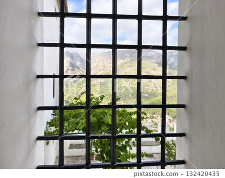 calm vantage point showing green mountain landscape through iron bars and stone surroundings 132420435