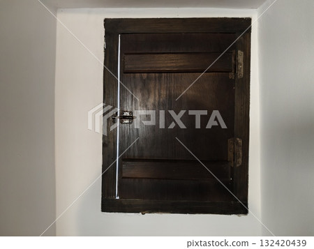 recessed wooden hatch with metallic latch, crafted dark wood hatch set into wall with iron latch 132420439