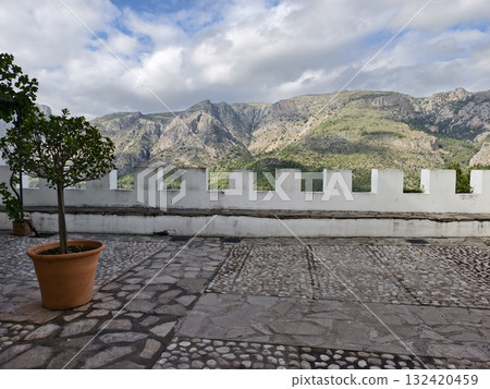 sunlit terrace with mountains nearby, terrace bathed in sunlight with trees and fortress feel 132420459