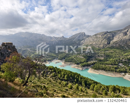 turquoise lake from rocky vantage, quaint turquoise reservoir observed from rocky outcrop with pines 132420461