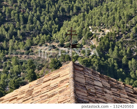 terracotta roof view, terracottatiled roof and metal cross overlooking green valleys and slopes 132420503