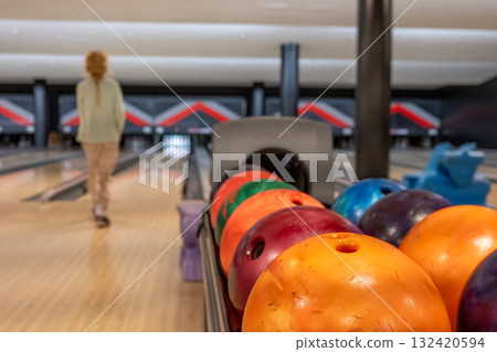 Bowler aiming for a strike in a modern bowling alley during an evening outing with friends Bowler aiming for a strike in a modern bowling alley during an evening outing with friends 132420594
