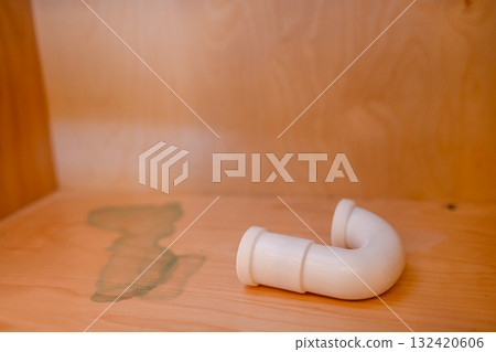Curved plumbing pipe resting on a wooden surface in a well-lit room during the daytime 132420606