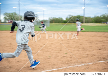 Young athlete runs towards home plate during a baseball game in a city park on a cloudy afternoon 132420611