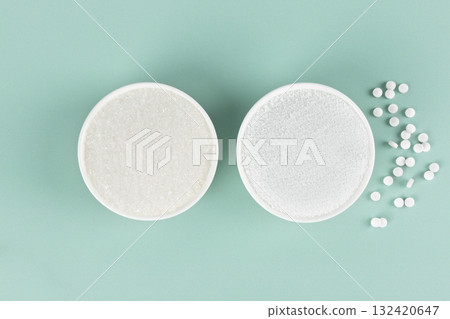 Two bowls: sugar and natural sweetener stevia on a blue background. Weight loss concept. Top view. Two bowls: sugar and natural sweetener stevia on a blue background. Weight loss concept. Top view. 132420647