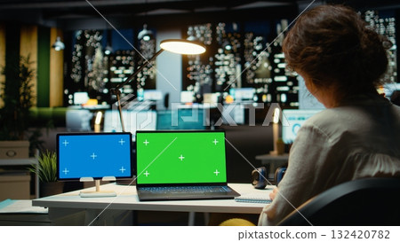 Executive manager at desk uses green screen on laptop and blue screen on tablet, scheduling new meetings and planning the weekly agenda. Business management tasks for a project. Camera A. 132420782
