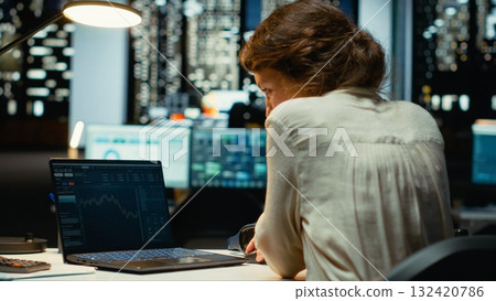 Professional worker in office monitors stock trends and candlestick charts on laptop, using data analysis, forecasting and finance strategy to optimize trading and achieve revenue goals. Camera B. 132420786