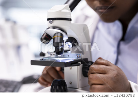 Close up of researcher focusing on a microscope with samples in chemistry lab. Using observation tool with tray for diagnostics, molecular analysis and discovery. Optics in bioscience. Close up of researcher focusing on a microscope with samples in chemistry lab. Using observation tool with tray for diagnostics, molecular analysis and discovery. Optics in bioscience. 132420798