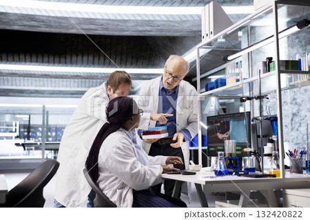 Scientists team handles blood samples in test tube within laboratory, conducting diagnostics, pathology and molecular biology experiments with vials to support healthcare innovation. 132420822