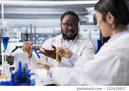 Teamworking lab colleagues inspecting liquids in test tube, looking for breakthroughs during clinical trials. Team of experts doing brainstorming, comparing chemicals vials, testing right formula 132420837