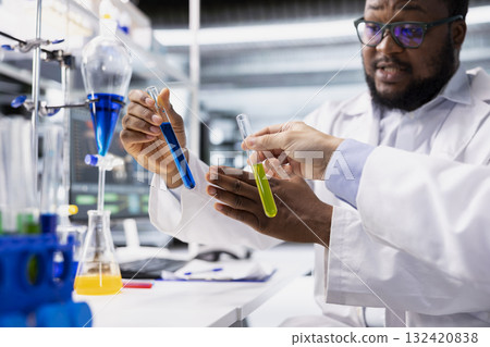 Close up of lab coworkers inspecting liquids in test tube, looking for breakthroughs during clinical trials. Team of specialists in research facility comparing chemicals vials, testing right formula Close up of lab coworkers inspecting liquids in test tube, looking for breakthroughs during clinical trials. Team of specialists in research facility comparing chemicals vials, testing right formula 132420838