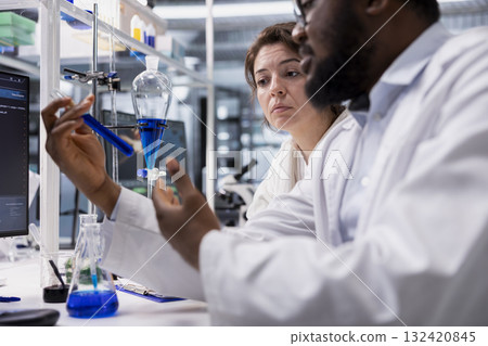 Lab coworkers inspecting reagents in test tube, looking for breakthroughs during clinical trials. Research facility specialist working together, comparing chemicals vials, testing right formula 132420845