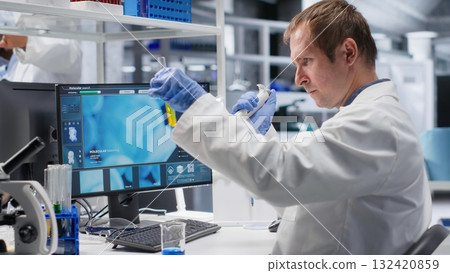 Researcher in clinical laboratory prepares solution with pipette and jars, mixing matter for genetics research and molecular analysis in biotechnology. Conducting advanced research study. 132420859