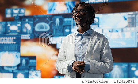 Joyous scientist reviewing medical scans projected on videowall. Happy researcher wearing lab coat standing in front of digital health dashboards backdrop, analyzing human anatomy, camera B Joyous scientist reviewing medical scans projected on videowall. Happy researcher wearing lab coat standing in front of digital health dashboards backdrop, analyzing human anatomy, camera B 132420871