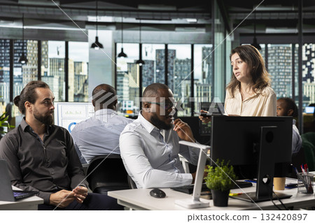 Diverse employees exchanging insights and new ideas to meet objectives, doing report sharing and forecasting at pc desk in the office. Work team managing business intel for development. Diverse employees exchanging insights and new ideas to meet objectives, doing report sharing and forecasting at pc desk in the office. Work team managing business intel for development. 132420897