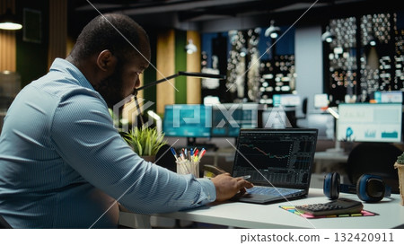 Angry concerned black man losing money with forex trend going down, seeing stock exchange indicators downward and worrying about bankruptcy late at night. Frustrated person being stressed. Angry concerned black man losing money with forex trend going down, seeing stock exchange indicators downward and worrying about bankruptcy late at night. Frustrated person being stressed. 132420911