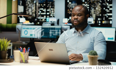 Black person proofreading and fact checking financial numbers, reviewing archived files after hours in the strategy room. Evaluating data on reports, researching and organizing agenda. Black person proofreading and fact checking financial numbers, reviewing archived files after hours in the strategy room. Evaluating data on reports, researching and organizing agenda. 132420912