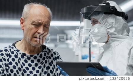 Researcher in secured lab treating infected patient in quarantine, recording virus symptoms and analyzing drug efficacy to develop a vaccine and breakthrough in medical protection. Camera B. 132420936