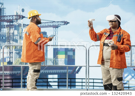 Offshore rig expert supervising deck operations using virtual reality technology, ensuring compliance with safety protocols. Engineer doing preventative maintenance on drilling rig with VR goggles 132420943