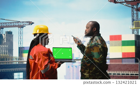 Chroma key laptop used by soldier on offshore platform communicating via military radio. Naval unit on drilling barge using green screen mockup notebook, speaking on walkie talkie, Chroma key laptop used by soldier on offshore platform communicating via military radio. Naval unit on drilling barge using green screen mockup notebook, speaking on walkie talkie, 132421021