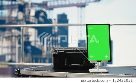 Vertical green screen tablet on offshore platform with software used to monitor equipment. Chroma key mockup device on drilling rig deck used to control offshore machinery and calibrate infrastructure Vertical green screen tablet on offshore platform with software used to monitor equipment. Chroma key mockup device on drilling rig deck used to control offshore machinery and calibrate infrastructure 132421031