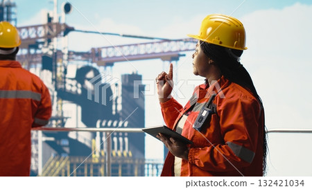 Team of offshore platform engineers supervising production activity on oil rig deck. Drilling rig specialists coordinating daily operations using devices, doing maintenance Team of offshore platform engineers supervising production activity on oil rig deck. Drilling rig specialists coordinating daily operations using devices, doing maintenance 132421034