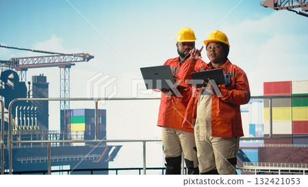 Offshore platform colleagues supervising deck operations with devices, ensuring compliance with safety protocols. Team of technicians doing equipment checkup on drilling rig, 132421053