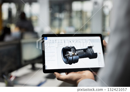 Close up of CAD designer using tablet app in office to upgrade turbine, boosting power output. Expert reviews eco turbine sensor data on touchscreen device to optimize efficiency 132421057