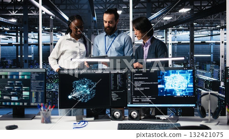 Happy data center coworkers monitoring neural network AI LLM visualization. Jolly workers in high tech facility using devices to oversee servers powering machine learning processes, camera A 132421075