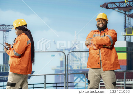Portrait of smiling technician inspecting integrity of offshore platform components to avoid downtime. Jolly man on drilling rig deck using diagnostic tools to detect malfunction in subsea pipelines Portrait of smiling technician inspecting integrity of offshore platform components to avoid downtime. Jolly man on drilling rig deck using diagnostic tools to detect malfunction in subsea pipelines 132421093