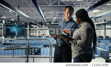 Technicians working together in server room, optimizing deep learning AI systems handling tasks. Data center coworkers doing brainstorming to adjust artificial intelligence model parameters, camera A 132421099