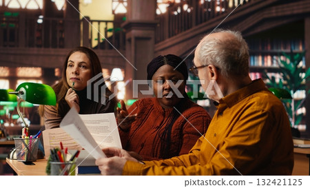 Mature team of performers rehearsing script dialogue together in a library, making drama play role preparations for character development. commitment to acting and dramaturgy. 132421125