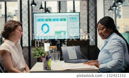 Human resources specialist evaluating the job application of a woman, discussing CV resume information during hiring interview, asking questions to ensure a successful meeting for employment. Camera B Human resources specialist evaluating the job application of a woman, discussing CV resume information during hiring interview, asking questions to ensure a successful meeting for employment. Camera B 132421152