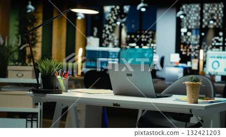 Modern empty office glows with the light of performance metrics and forecasting graphs. Corporate space equipped with technology and computers reflects administration of enterprise objectives. Modern empty office glows with the light of performance metrics and forecasting graphs. Corporate space equipped with technology and computers reflects administration of enterprise objectives. 132421203