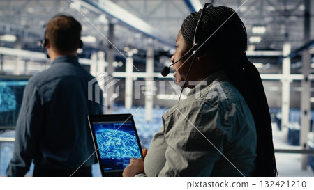 Team of data center programmers use AI to help customers resolve website hosting problems. Teamworking server farm tech support experts help users keep their online services running smoothly, camera B 132421210