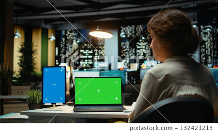 Business consultant works with mockup copy space on tablet and laptop, researching reports for a management project. Collecting information and solving tasks late at night, work after hours. Camera A. 132421213