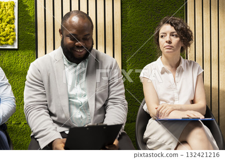 Nervous businesswoman in the hallway awaiting her turn for the interview, preparing her speech to meet the recruiter. Candidates sitting in the queue with strong qualifications on the resume. Nervous businesswoman in the hallway awaiting her turn for the interview, preparing her speech to meet the recruiter. Candidates sitting in the queue with strong qualifications on the resume. 132421216