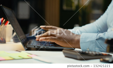 Close up of black worker proofreading and fact checking financial data, reviewing archived files after hours in strategy room. Evaluating reports, researching and organizing agenda. Close up of black worker proofreading and fact checking financial data, reviewing archived files after hours in strategy room. Evaluating reports, researching and organizing agenda. 132421221