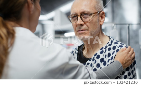 Female researcher encouraging her old patient with illness in laboratory, making progress in healthcare innovation. Reassuring and consoling for a man agreeing to clinical trial. Camera B. 132421230