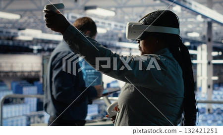 Software developer in server room wearing VR goggles optimizing deep learning systems handling tasks. African american woman in data center adjusts AI model parameters using virtual reality, camera B Software developer in server room wearing VR goggles optimizing deep learning systems handling tasks. African american woman in data center adjusts AI model parameters using virtual reality, camera B 132421251