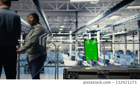 Data center workers monitor AI processes with isolated screen tablet, reviewing metrics. Engineers use chroma key device to review artificial intelligence reports during inspection, camera A 132421273
