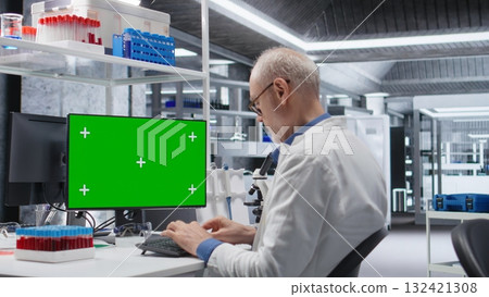 Green screen on monitor next to male researcher working in laboratory with medical tools, focusing on healthcare and biotechnology. Molecular science for pharmaceutical discovery. Green screen on monitor next to male researcher working in laboratory with medical tools, focusing on healthcare and biotechnology. Molecular science for pharmaceutical discovery. 132421308