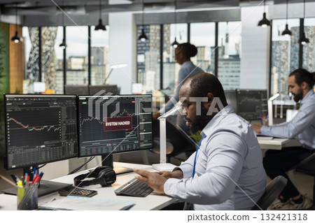 Prop firm trader seeing warning popup of hacking activity, working to secure account. African american man reacting to stock market account perpetrated by hackers looking to gain trade secrets 132421318