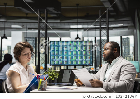 African american candidate presenting resume information with HR worker during job interview meeting in a business space. Career development and potential employment with his qualifications. African american candidate presenting resume information with HR worker during job interview meeting in a business space. Career development and potential employment with his qualifications. 132421367