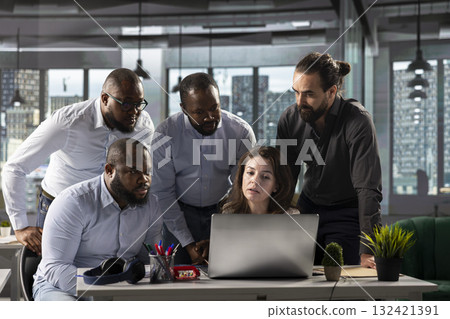 Coworkers engaged in consulting and report sharing at workplace. Professional team reviews visual data and documents to enhance business strategy and performance goals for monthly targets. 132421391
