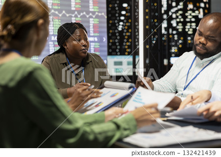 Marketing team evaluating sales and profit within infographics data, coworkers sharing insight in a briefing conference at night. Staff members planning activities for a better public image. 132421439