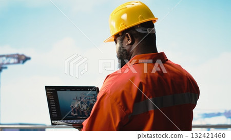 Fossil fuel company expert using laptop software to determine optimal drilling rig locations. African american man on offshore platform looking at well sites data on notebook 132421460