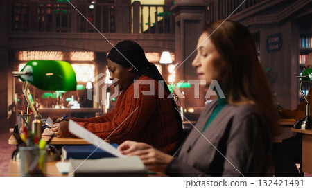 Mature woman student in the library highlighting important ideas for exams, focusing on her studies surrounded by academic materials and books. Study strategy memorization. Mature woman student in the library highlighting important ideas for exams, focusing on her studies surrounded by academic materials and books. Study strategy memorization. 132421491