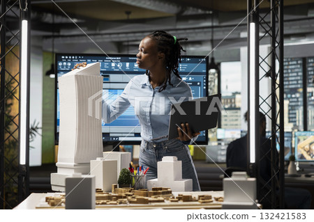Black female developer reviewing zoning regulations with 3D models, residential project with a master plan for sustainable housing development aligned with smart city infrastructure growth. Black female developer reviewing zoning regulations with 3D models, residential project with a master plan for sustainable housing development aligned with smart city infrastructure growth. 132421583